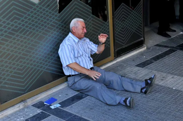 A pensioner collapses outside a bank during the capital controls period in 2015 Greece